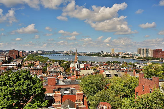 Panoramic view of a cityscape with a river and numerous buildings.