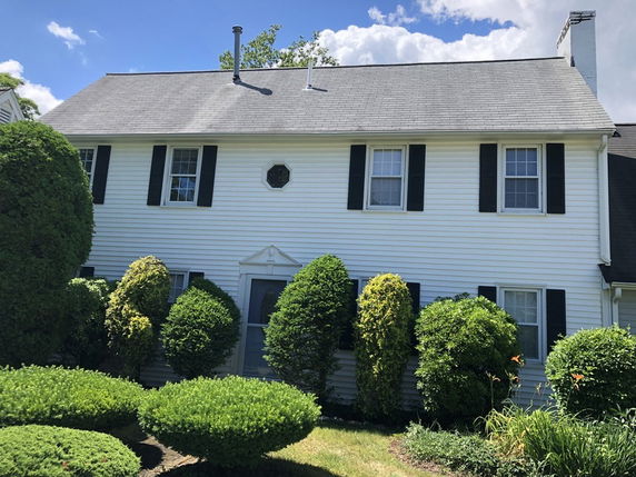 Front view of a two-story house with white siding and black shutters.