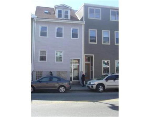 Front view of a three-story residential building with multiple windows and a sloped roof.