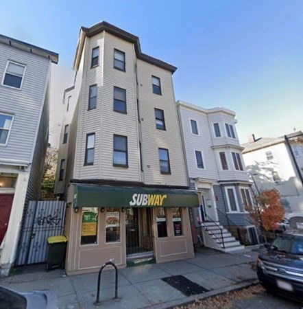 Front view of a three-story building with a Subway restaurant on the ground floor.