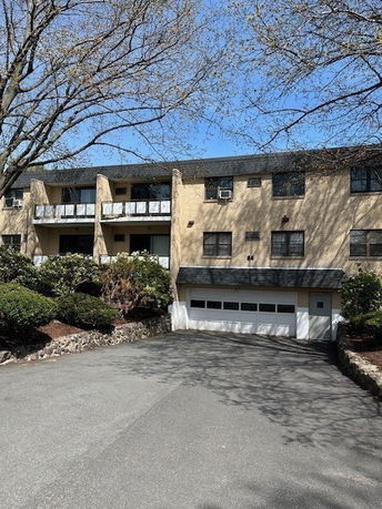 Front view of a multi-story building with balconies and a garage entrance.