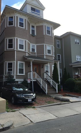 Front view of a multi-story house with bay windows and a covered front porch.