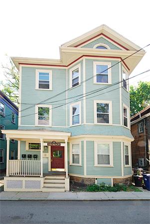 Front view of a three-story house with a porch and a gabled roof.