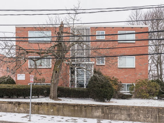 Front view of a brick apartment building with multiple windows.