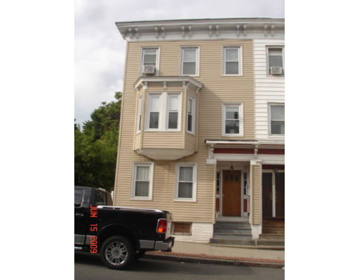 Front view of a three-story house with a bay window and stairs leading to the entrance.