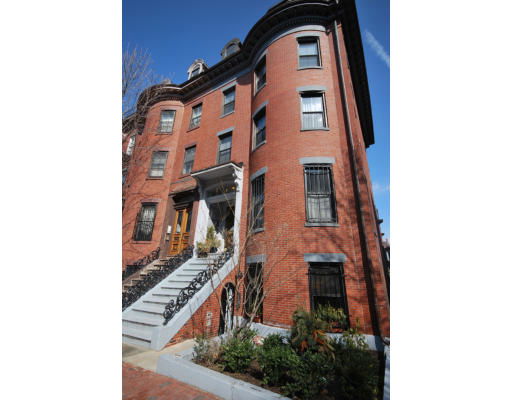 Front view of a multi-story brick building with stairs leading to the entrance.