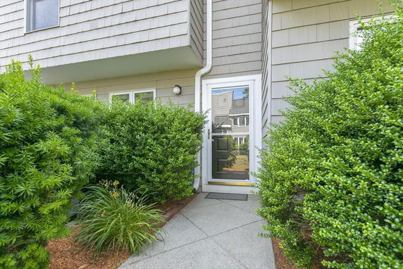 Front view of a house with a side entrance surrounded by bushes.