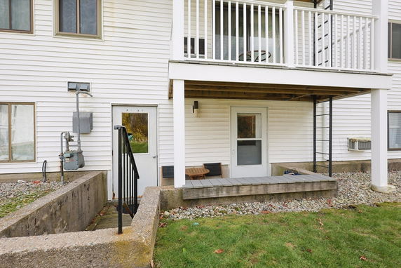 Rear view of a house with a lower ground entrance and a balcony above.