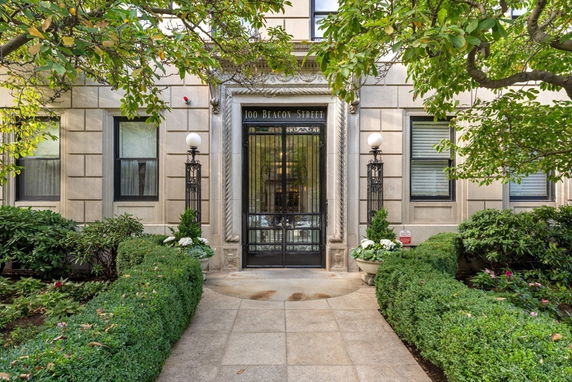 Front view of a building entrance with decorative iron gate and surrounding greenery.