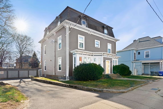 Front view of a multi-story house with a gabled roof and dormer windows.
