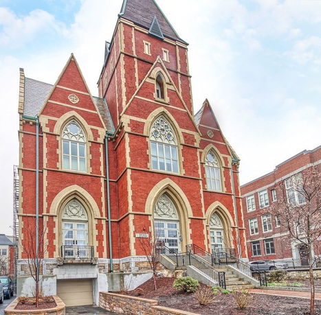 Front view of a red brick building with gothic architectural features and large arched windows.