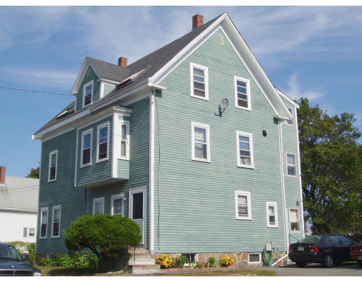 Side view of a multi-story house with green siding and multiple windows.