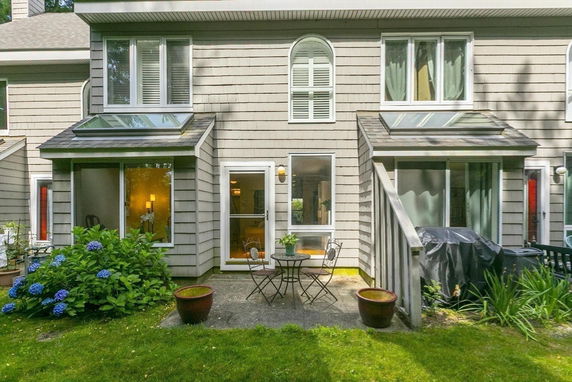 Back view of a two-story house with patio and skylights.