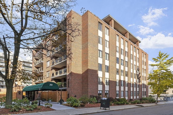 Front view of a multi-story brick apartment building with balconies.