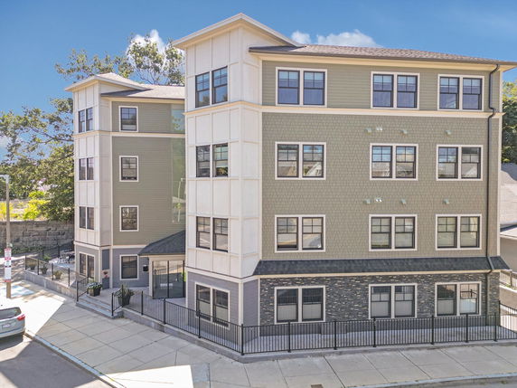 Front view of a multi-story building with multiple windows and a fence.