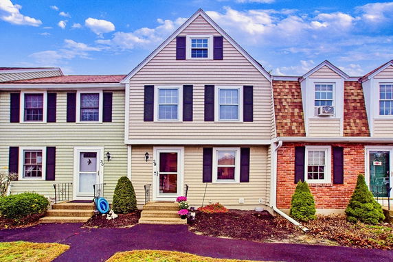Front view of a two-story townhouse with siding and brick facade.