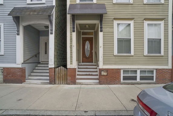 Front view of a two-story house with a wooden door and brick foundation.