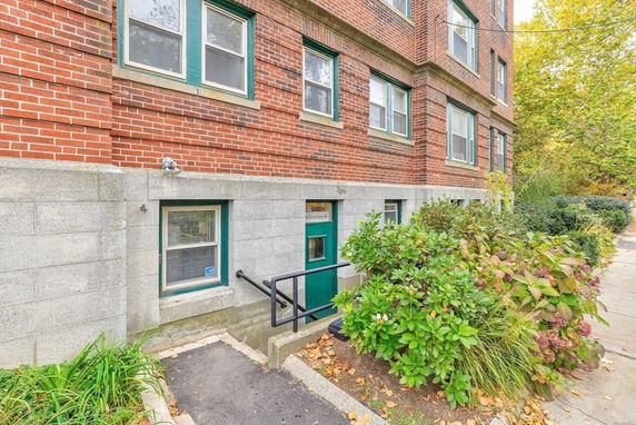 Front view of a brick apartment building with a green door and windows.
