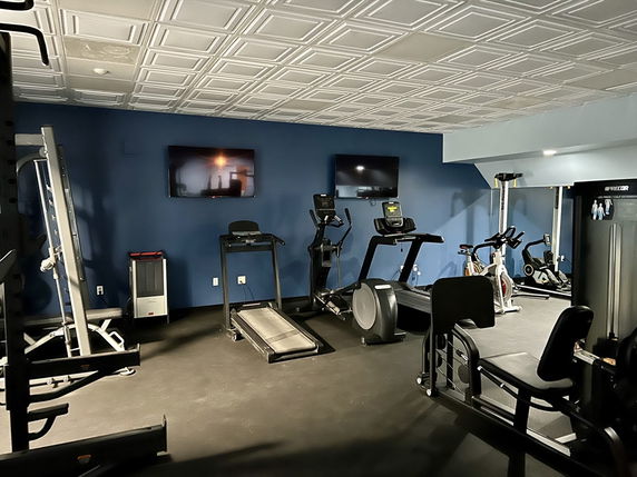 Indoor gym area with exercise equipment including treadmills, exercise bikes, and weight machines.