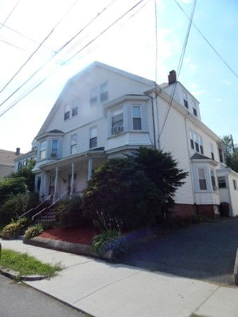 Front view of a multi-story residential house with a porch and driveway.