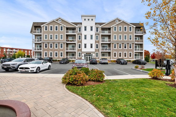 Front view of a multi-story residential building with a parking area in front.
