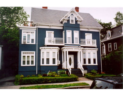 Front view of a two-story house with a gabled roof and decorative balconies.