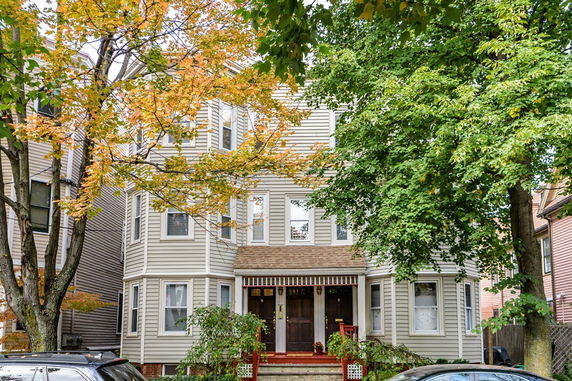 Front view of a multi-story residential building with multiple windows and a front entrance.