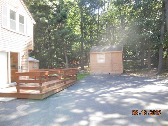 Outdoors view showing a house and a small shed surrounded by trees.