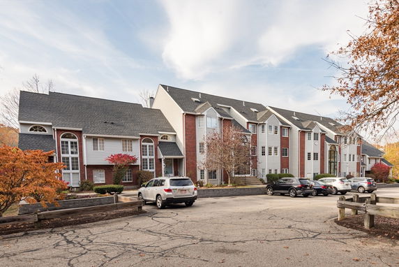 Front view of a multi-story residential building with parking area.