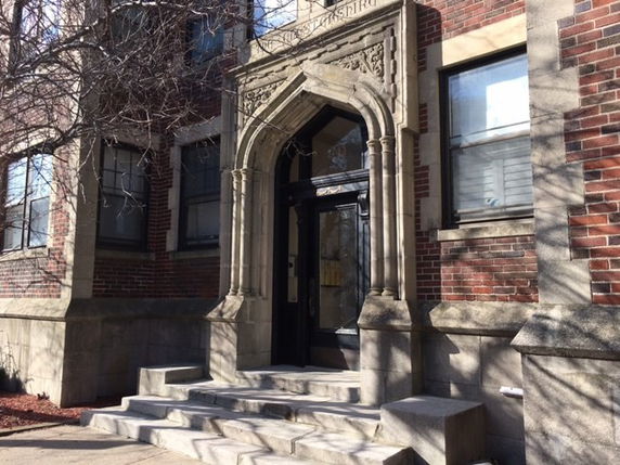 Front view of a brick building entrance with an ornate stone archway.