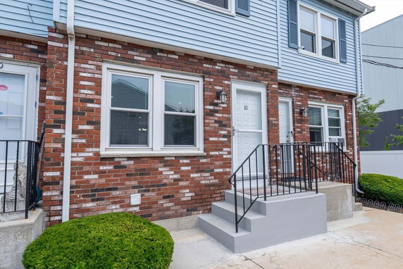 Front view of a brick townhouse with two doors and a staircase.