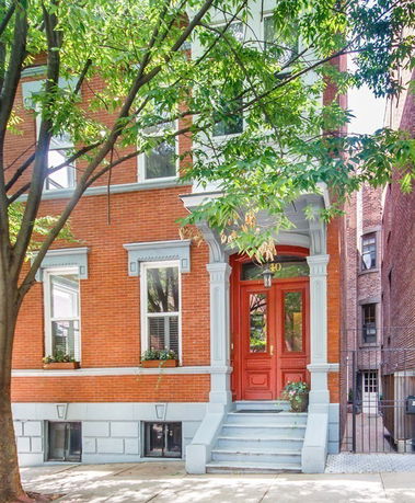 Front view of a brick building with red door and windowsills.