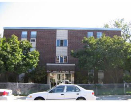 Front view of a three-story brick building with trees partially obscuring the facade.