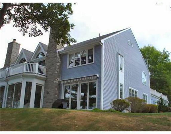 Front view of a multi-story house with large windows and a chimney.