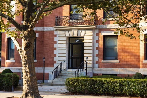 Front view of a brick building with a central entrance and iron railings.