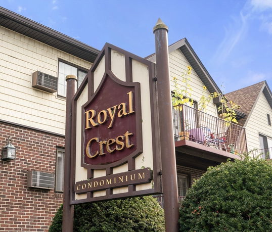 Front view of a building with a sign reading 'Royal Crest Condominium'.