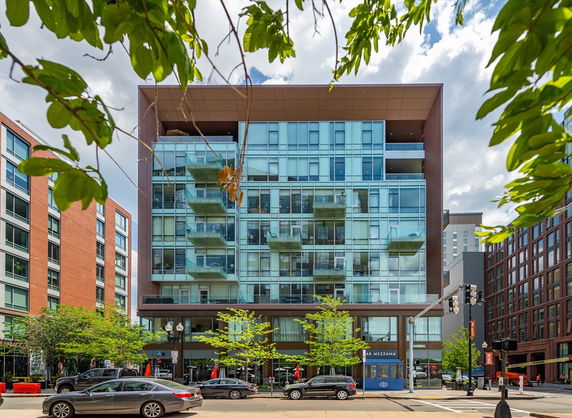 Front view of a modern multi-story building with glass balconies and a restaurant on the ground floor.