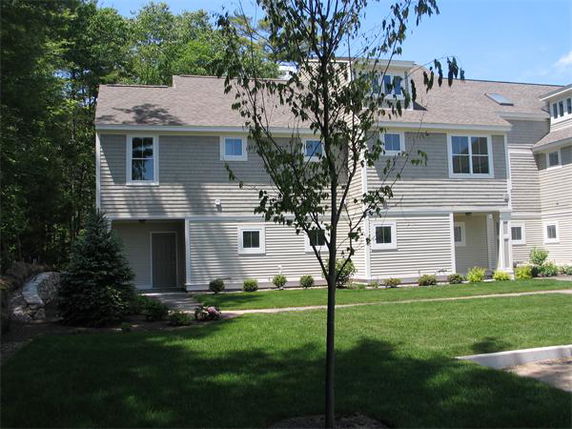 Front view of a two-story residential building with beige siding and multiple windows.