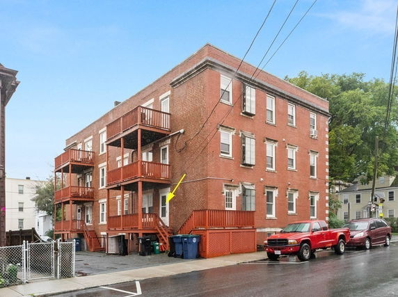 Front view of a multi-story brick apartment building with balconies.