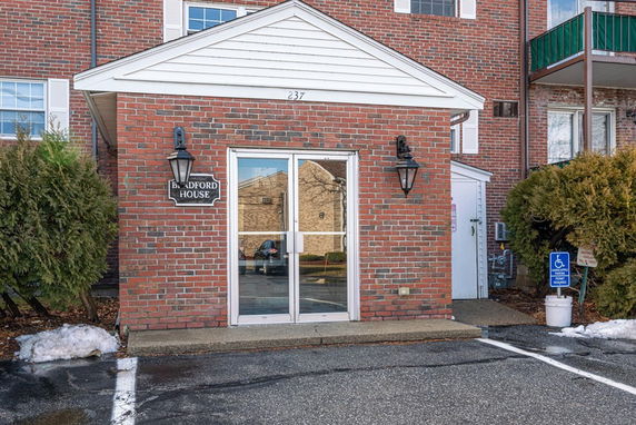 Front view of a brick building entrance with glass doors and a small porch.