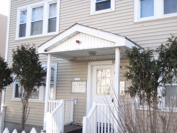 Front view of a house with a small porch and white siding.