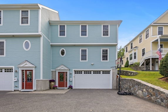 Front view of a multi-story house with garages and red doors.