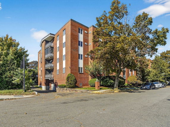 Front view of a multi-story brick apartment building with balconies.