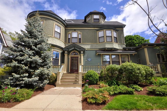 Front view of a large multi-story house with a unique architectural design and a prominent entrance.