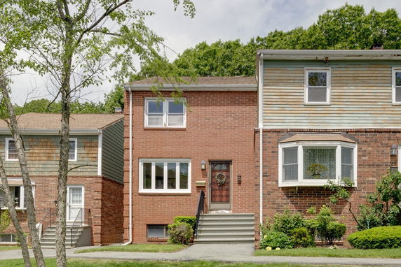 Front view of a two-story brick house with steps leading to the entrance.