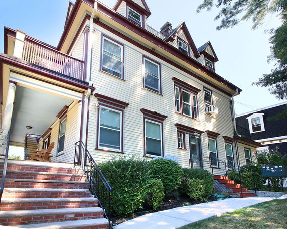 Front view of a multi-story house with a staircase leading to the entrance.