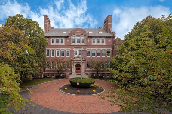 Front view of a multi-story brick building with decorative entrance and circular driveway.