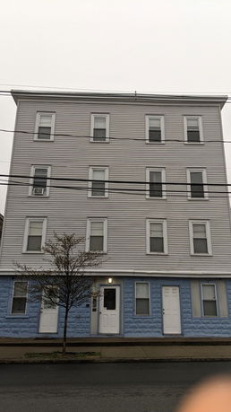 Front view of a multi-story residential building with several windows and two entrance doors.
