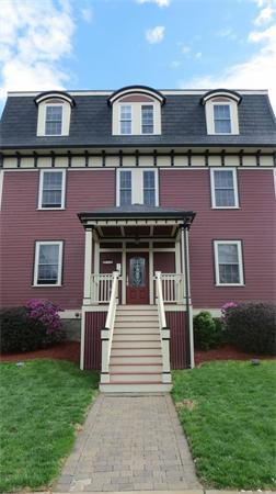 Front view of a three-story house with a front porch and stairs leading up to the entrance.