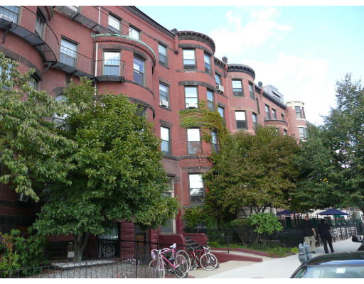 Front view of a multi-story brick building with rounded architectural features and balconies.